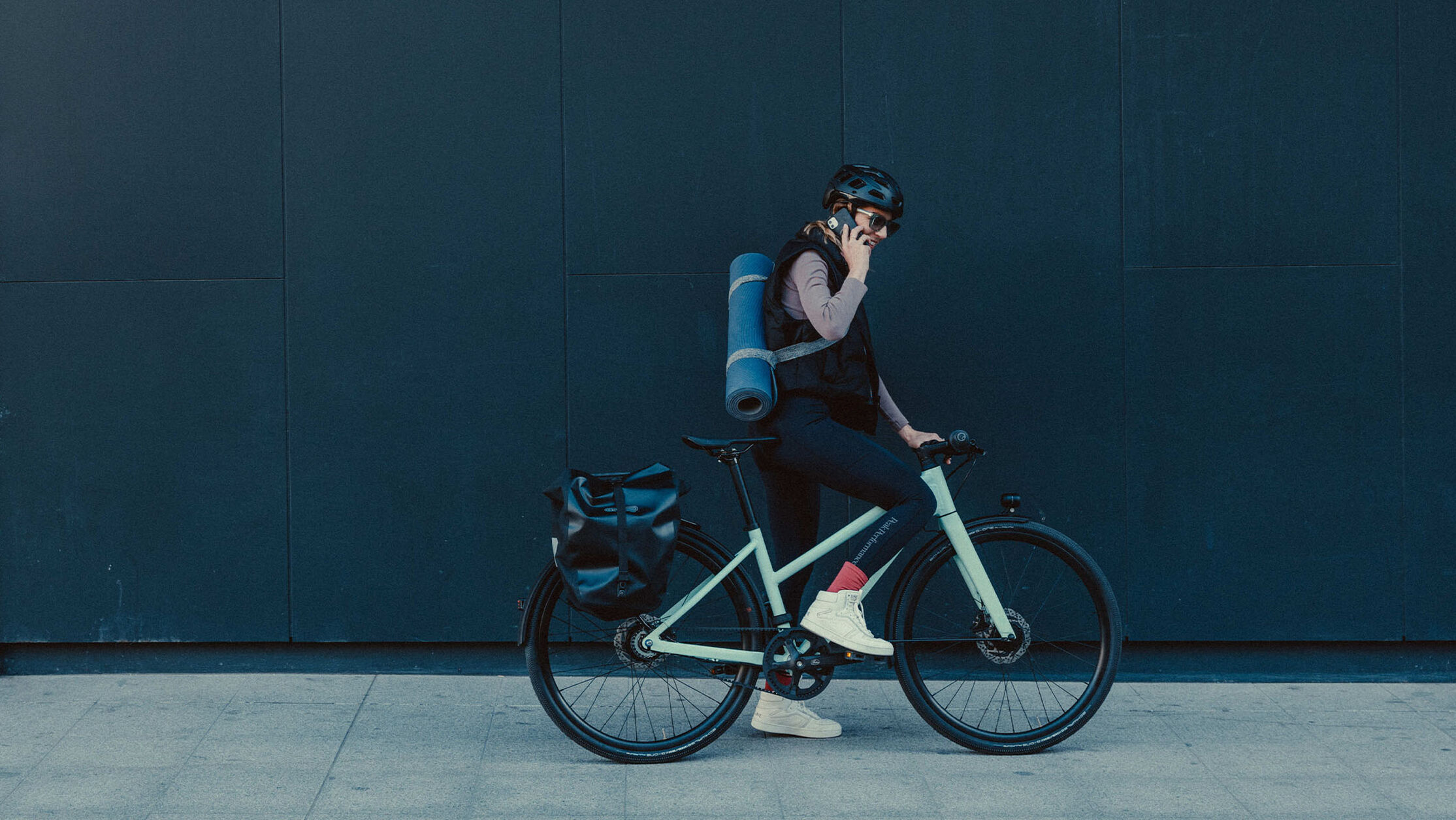 Man sitting on stone steps beside a Canyon bike, adjusting his camera in a park setting.